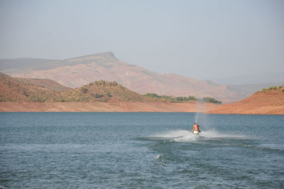 Man riding boat on sea against clear sky