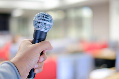 Close-up of hand holding microphone in auditorium