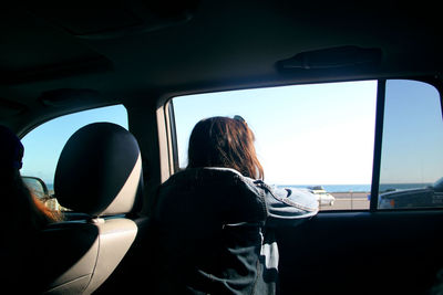 Rear view of woman looking through window while sitting in car