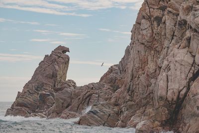 Rock formation on beach against sky