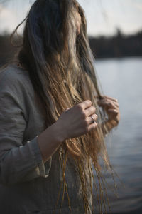 Close up woman in linen clothes touching strands of gray brown hair portrait picture