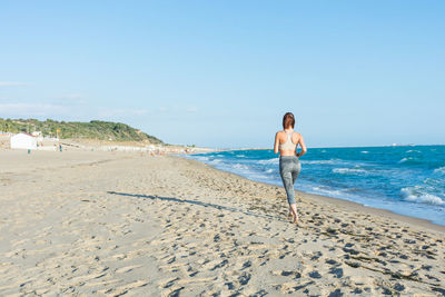 Woman standing on beach against clear sky