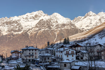 Houses and snowcapped mountains against clear sky