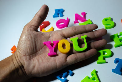 Close-up of hand holding multi colored text