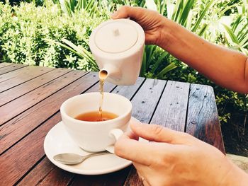 Cropped image of person pouring tea