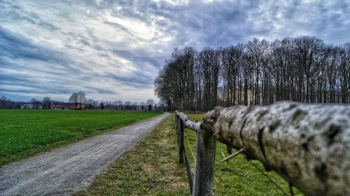 Empty road amidst field against sky