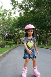 Full length of girl roller skating on road against trees