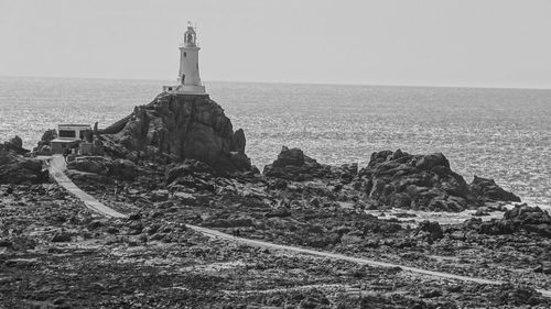 Lighthouse on beach against clear sky