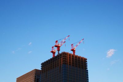 Low angle view of cranes on building against sky