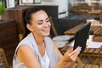 Beautiful businesswoman with smile sitting with touchpad in cozy restaurant person