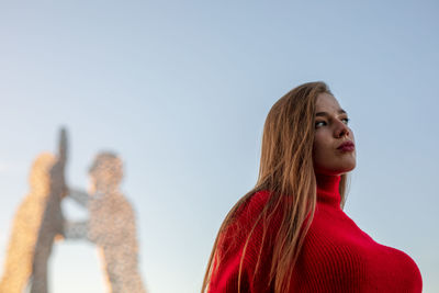 Young woman standing against clear sky