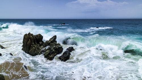 Waves splashing on shore against sky