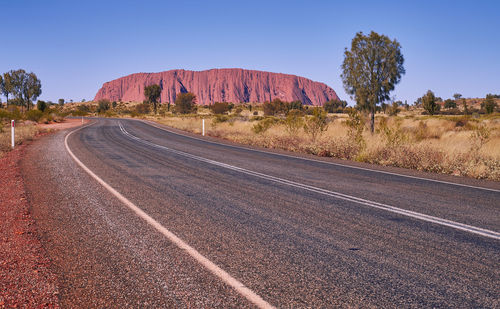 Road by land against clear blue sky