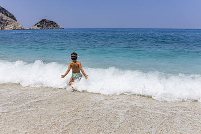 Full length of boy on beach against sky