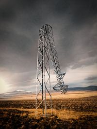 Low angle view of electricity pylon on field against sky