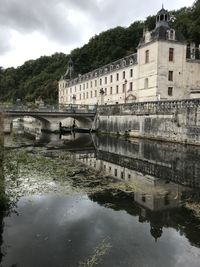 Bridge over river by buildings against sky