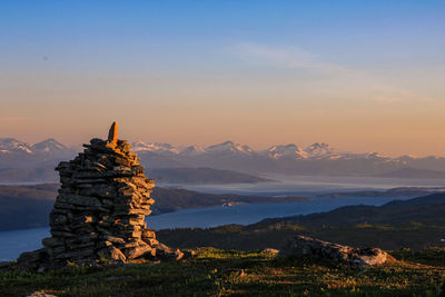 Stack of rock on landscape against sky during sunset