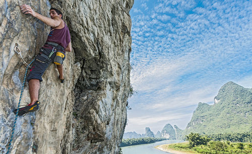 Young man climbing steep rock face in yangshuo / china