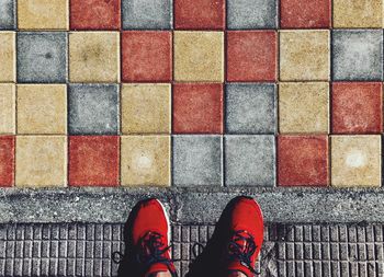 Low section of person standing on multi colored tiled floor