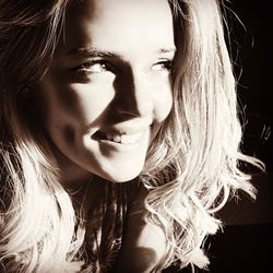 Close-up portrait of young woman against black background