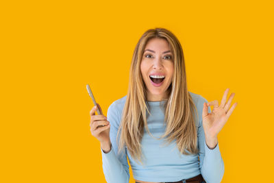 Portrait of young woman against yellow background