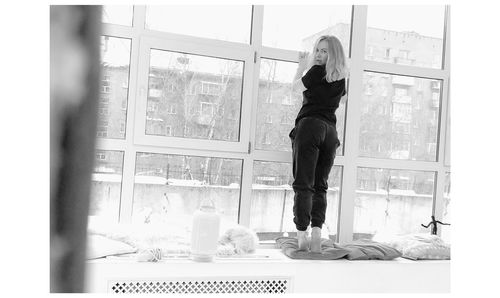 Portrait of woman standing by window at home