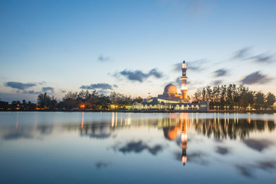 Reflection of illuminated tower in lake at sunset