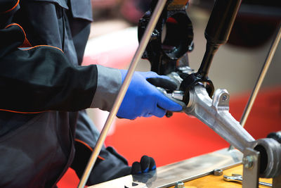 Close-up of manual worker repairing machinery while working in workshop