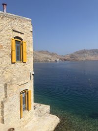 Building by sea against clear blue sky