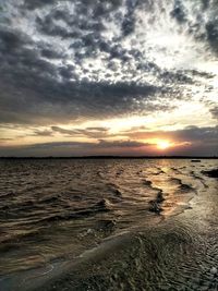 Scenic view of sea against dramatic sky during sunset