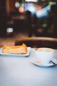 Cappuccino with snack served on table in cafe