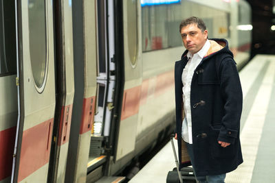 Man with luggage standing at railroad station platform