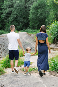A family walking hand in hand on a scenic nature trail surrounded by greenery and natural beauty