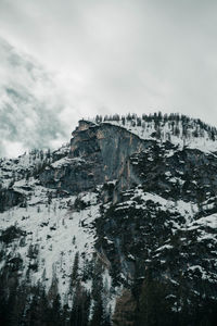 Low angle view of rock formation against sky during winter