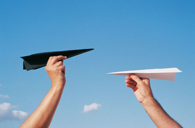 Low angle view of person hand against blue sky