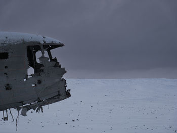 Abandoned boat on beach against sky during winter