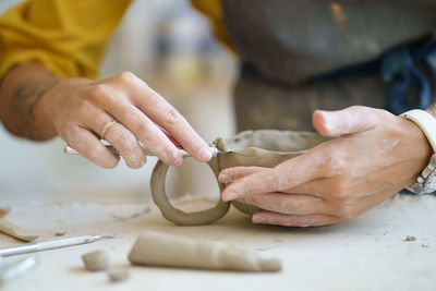 Female potter molding clay cup. hands of professional ceramist create pottery crockery at workshop