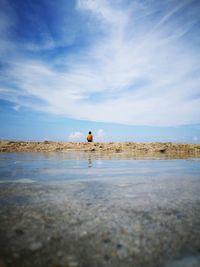 Surface level view of boy at beach against sky
