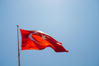 Low angle view of flag against clear blue sky