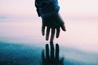 Cropped hand of woman touching sea shore