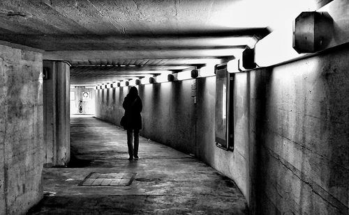 Rear view of man walking in illuminated tunnel