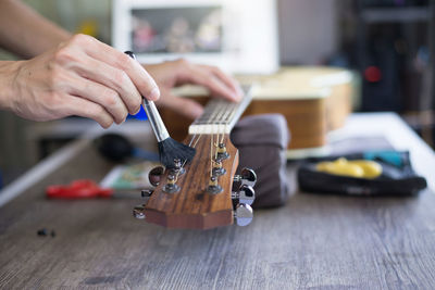 Cropped hand of person painting guitar at workshop