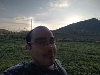 Portrait of young man wearing sunglasses on field against sky