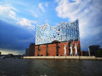 Building by river against cloudy sky