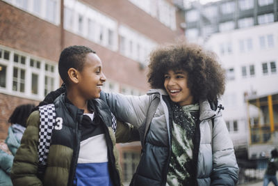 Happy friends with arm around each other in school campus