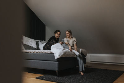 Homosexual female couple sitting on bed and looking at cell phone