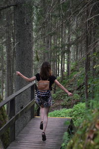 Full length of woman jumping over boardwalk