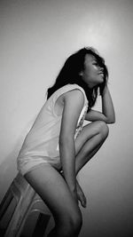 Side view of woman sitting against wall