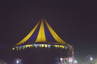Illuminated ferris wheel against sky at night