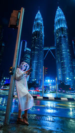 Woman using digital tablet against illuminated buildings in city at night